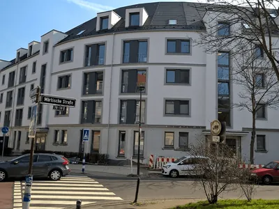 Helles Eckgebäude mit Mansarddach an einer Straßenkreuzung