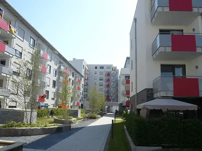 Wohnanlage mit roten Balkonbrüstungen und begrüntem Innenhof